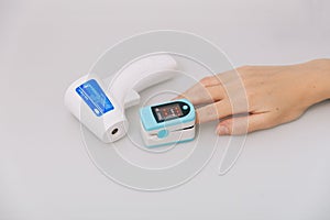 Pulse oximeter and thermometer gun on white background. Infrared isometric thermometer gun to check body temperature for