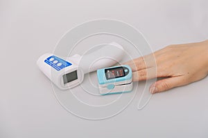 Pulse oximeter and thermometer gun on white background. Measuring oxygen saturation, pulse rate and oxygen levels