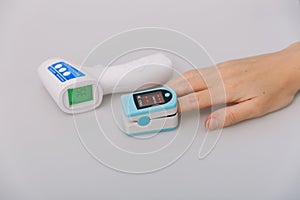 Pulse oximeter and thermometer gun on white background. Measuring oxygen saturation, pulse rate and oxygen levels