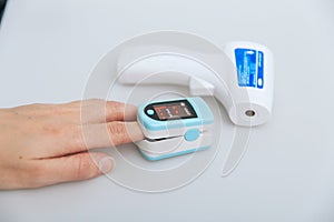 Pulse oximeter and thermometer gun on white background. Measuring oxygen saturation, pulse rate and oxygen levels