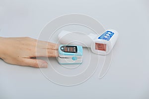 Pulse oximeter and thermometer gun on white background. Measuring oxygen saturation, pulse rate and oxygen levels