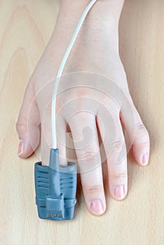 Pulse Oxymeter on a finger, isolated on a wood background