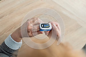 Pulse Oxymeter on a woman finger hand on a wooden table. Top view. photo