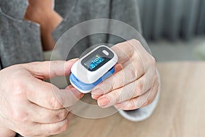 Pulse Oxymeter on a woman finger hand on a wooden table. Top view.