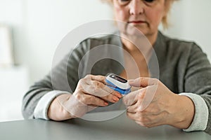 Pulse Oxymeter on a woman finger hand on a wooden table. Top view. photo