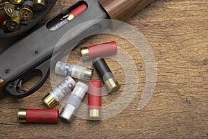 Pump action shotgun and bullet shells on wooden background