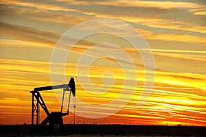 Pump jack in the oil field at sunset