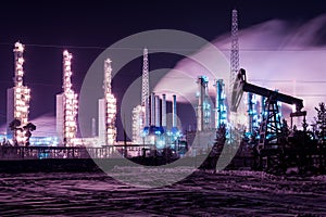 Pump jack and refinery night. Chemical industry distillation towers detail at night. Oil gas theme.