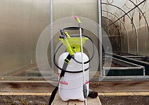 Pump sprayer against the backdrop of an open greenhouse