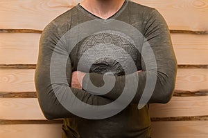 Pumped-up male body athletic person in clothes posing idly wooden background, close up