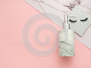 Pumper and false eyelashes on marble and pink background