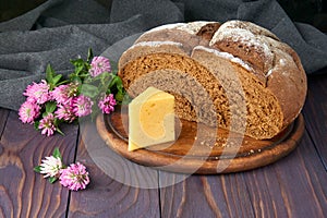 Pumpernickel - bread made with a combination of rye flour and whole rye grains. Cheese, clover flowers. Fresh healthy farm food