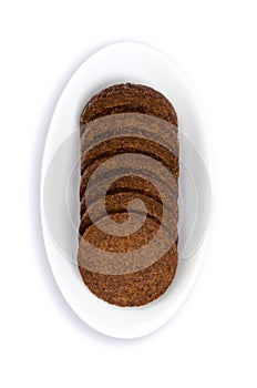Pumpernickel slices, circle shaped disks of dark brown rye bread, in white bowl