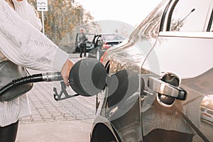Pumping gas fuel car at oil station. Woman hand refuel petrol nozzle tank. Refueling transportation and Automotive industry