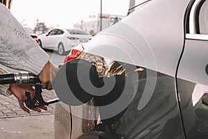 Pumping gas fuel car at oil station. Woman hand refuel petrol nozzle tank. Refueling transportation and Automotive industry