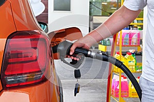 Pumping gasoline fuel in orange car at a gas station. To fill car with fuel in petrol station. Petrol station pump. Close up