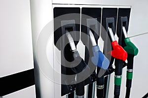 Pumping  red green blue black Guns for refueling at a gas oil diesel station on a sunset day . Car pulls up to refuel . Service