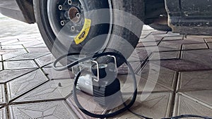 Pumping a spare wheel on the car using an air compressor. Wheel hub and air supply cable for inflating car tires