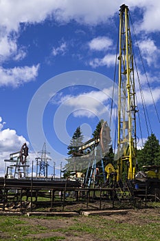 The pumping units and well workover operation. Oil Pump Jack Sucker Rod Beam and Workover Rig Working on Oil Well. Oil and gas