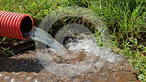 Pumping water from the flood zone. Sewage system. Industrial wastewater. Sewer drains from a plastic corrugated red sewer pipe