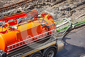 Pumping water from sewage canals during the construction of roads in the city. Truck with orange water tank