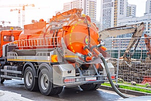 Pumping water from sewage canals during the construction of roads in the city. Truck with orange water tank