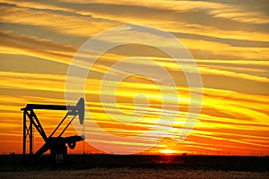 Pumpjack in the oil field at sunset