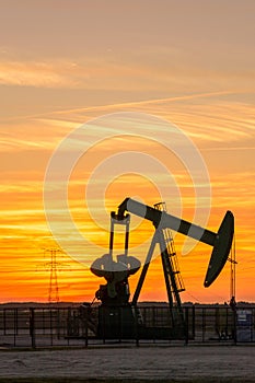 Pumpjack and transmission tower at sunset symbolizing energy transition