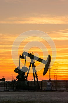 Pumpjack and transmission towers at sunset symbolizing energy transition