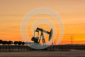 Pumpjack and transmission towers at sunset symbolizing energy transition