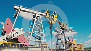 Pumpjacks operate on oil field against blue sky on sunny day