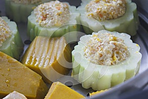 Pumpkin and bitter melon stuffed with vermicelli, tofu, corn and carrot while steaming in steaming pot