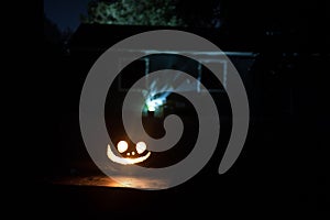 Pumpkin Burning In Forest At Night - Halloween Background. Scary Jack o Lantern smiling and glowing pumpkin with dark toned foggy