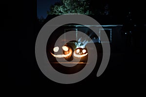 Pumpkin Burning In Forest At Night - Halloween Background. Scary Jack o Lantern smiling and glowing pumpkin with dark toned foggy
