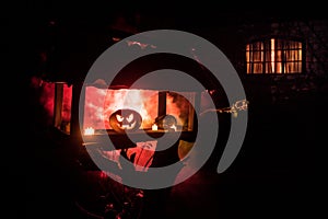 Pumpkin Burning In Forest At Night - Halloween Background. Scary Jack o Lantern smiling and glowing pumpkin with dark toned foggy