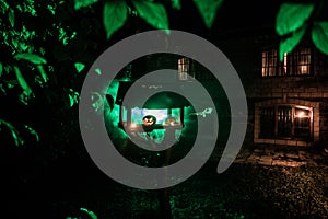 Pumpkin Burning In Forest At Night - Halloween Background. Scary Jack o Lantern smiling and glowing pumpkin with dark toned foggy