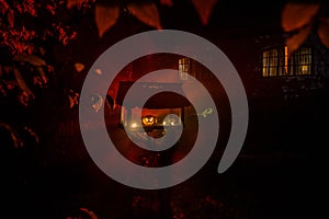 Pumpkin Burning In Forest At Night - Halloween Background. Scary Jack o Lantern smiling and glowing pumpkin with dark toned foggy