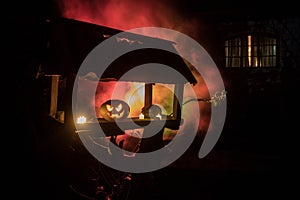 Pumpkin Burning In Forest At Night - Halloween Background. Scary Jack o Lantern smiling and glowing pumpkin with dark toned foggy