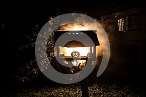 Pumpkin Burning In Forest At Night - Halloween Background. Scary Jack o Lantern smiling and glowing pumpkin with dark toned foggy