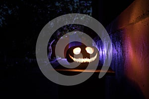 Pumpkin Burning In Forest At Night - Halloween Background. Scary Jack o Lantern smiling and glowing pumpkin with dark toned foggy