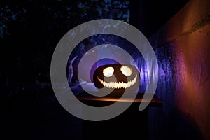 Pumpkin Burning In Forest At Night - Halloween Background. Scary Jack o Lantern smiling and glowing pumpkin with dark toned foggy