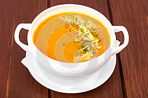 Pumpkin carrot cream soup with parmesan and green shoots of watercress