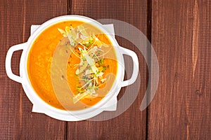 Pumpkin carrot cream soup with parmesan and green shoots of watercress