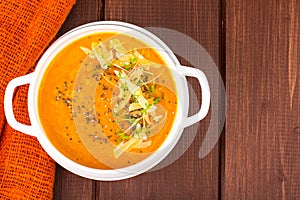 Pumpkin carrot cream soup with parmesan and green shoots of watercress