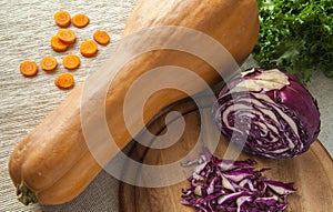 Pumpkin with carrot slices, fresh salad and purple cabbage on a wooden table