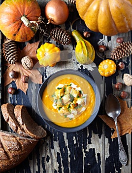 Pumpkin and carrot soup with cream, croutons on old dark wooden background. For Thanksgiving, halloween. Top view.