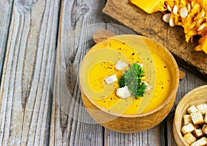 Pumpkin and carrot soup, tadka with cream and parsley on dark wooden background. Top view