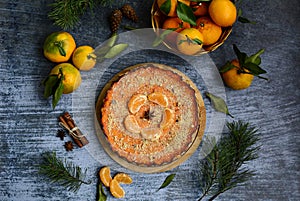 Pumpkin and citrus pie, tangerines, spruce twigs and cones, cinnamon sticks on a blue background