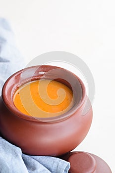 Pumpkin cream soup in a ceramic bowl on a white table. Copy space