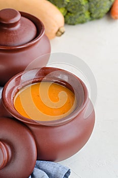 Pumpkin cream soup in a ceramic bowl on a white table. Copy space